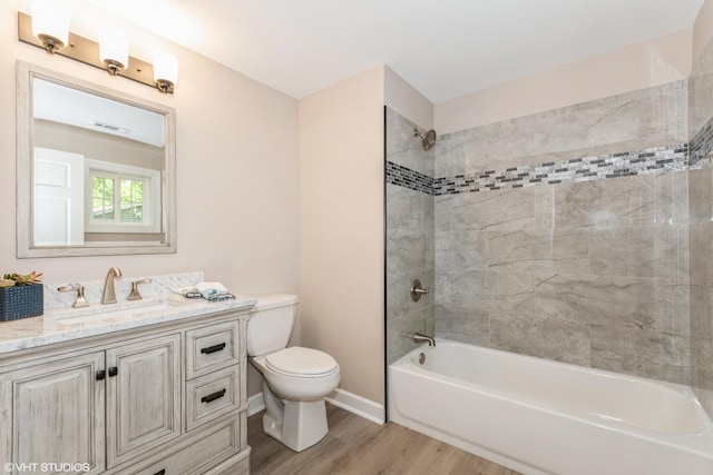 full bathroom featuring vanity, hardwood / wood-style flooring, toilet, and tiled shower / bath