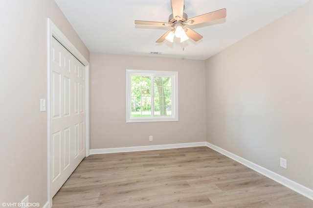 unfurnished bedroom with light hardwood / wood-style flooring, a closet, and ceiling fan