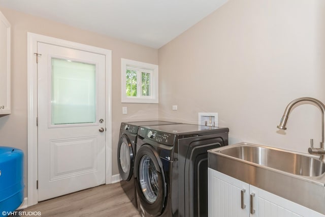 laundry area with cabinets, sink, washer and dryer, and light wood-type flooring