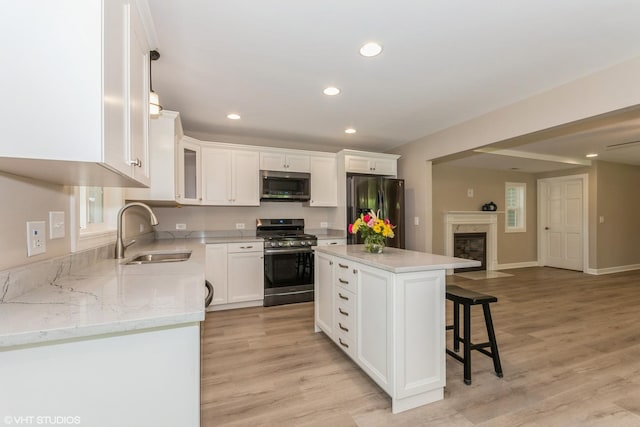 kitchen with sink, appliances with stainless steel finishes, white cabinetry, hanging light fixtures, and a center island