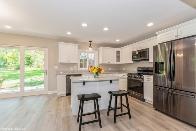 kitchen with white cabinetry, appliances with stainless steel finishes, a kitchen island, and light hardwood / wood-style flooring