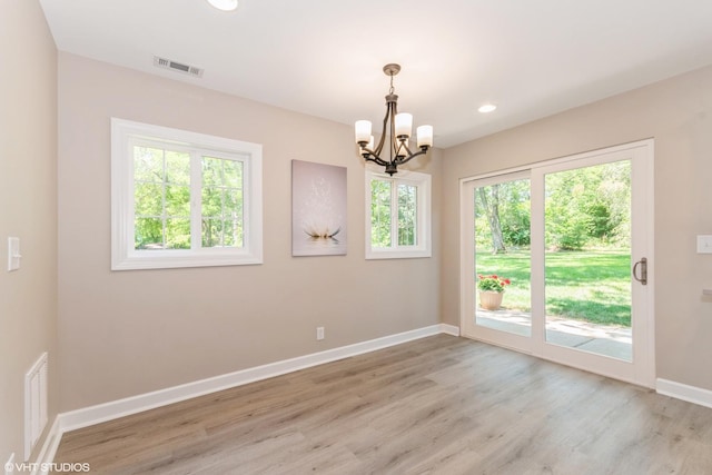 unfurnished room featuring an inviting chandelier and light wood-type flooring