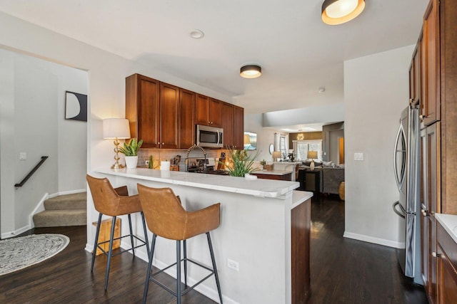 kitchen featuring appliances with stainless steel finishes, dark wood-type flooring, a breakfast bar area, and kitchen peninsula