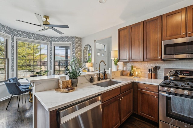 kitchen featuring stainless steel appliances, tasteful backsplash, sink, and kitchen peninsula