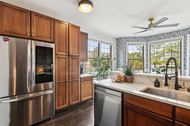 kitchen featuring dark wood-type flooring, sink, light stone counters, appliances with stainless steel finishes, and ceiling fan