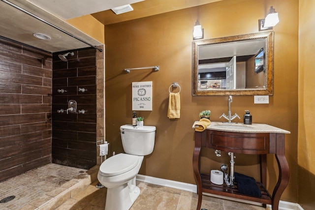 bathroom featuring sink, a tile shower, and toilet