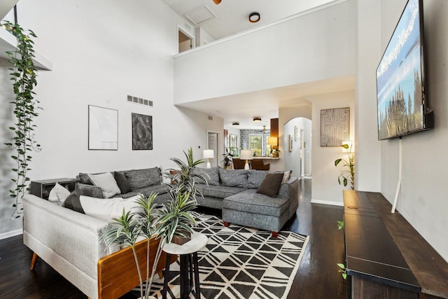 living room with a towering ceiling and dark hardwood / wood-style flooring