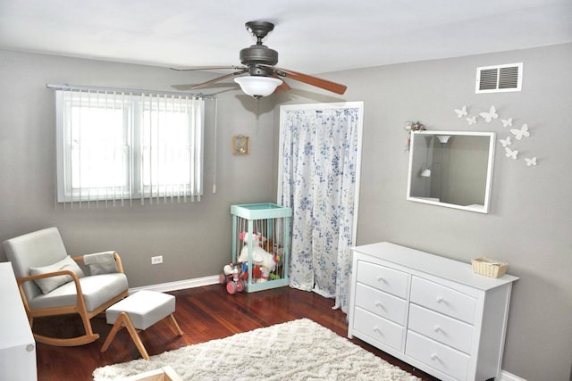 living area featuring dark wood-type flooring and ceiling fan