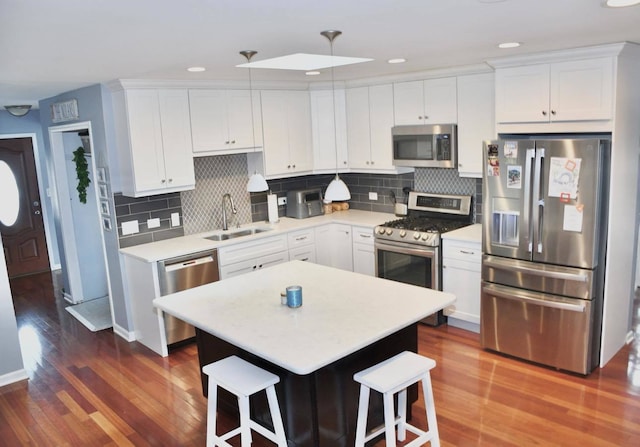 kitchen featuring sink, a center island, a kitchen breakfast bar, stainless steel appliances, and white cabinets