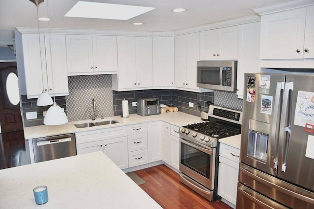 kitchen featuring dark wood-type flooring, sink, appliances with stainless steel finishes, white cabinets, and backsplash