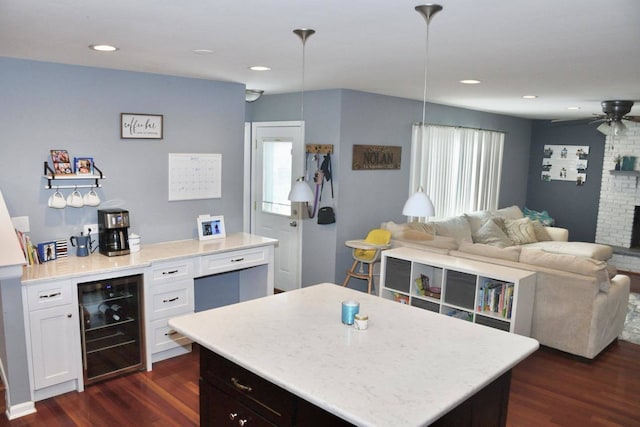 kitchen with pendant lighting, white cabinets, beverage cooler, dark hardwood / wood-style flooring, and a center island