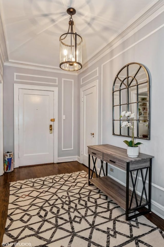 entryway with a chandelier, ornamental molding, wood finished floors, and baseboards