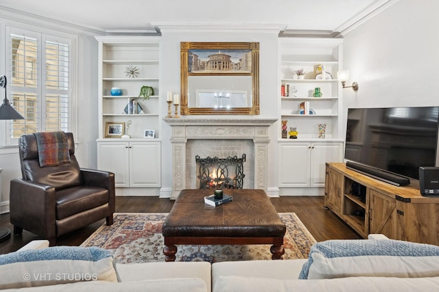 living area with a lit fireplace, dark wood finished floors, built in features, and crown molding