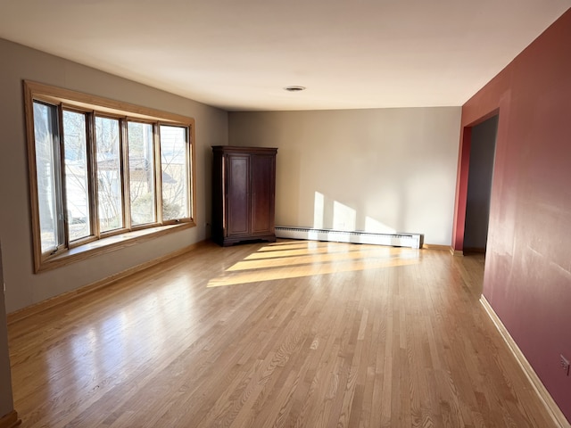 unfurnished room featuring a baseboard radiator and light wood-type flooring