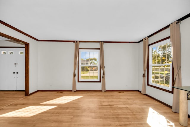 empty room with ornamental molding, a healthy amount of sunlight, and light wood-type flooring