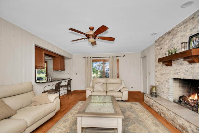 living room with ceiling fan, a fireplace, and light hardwood / wood-style floors