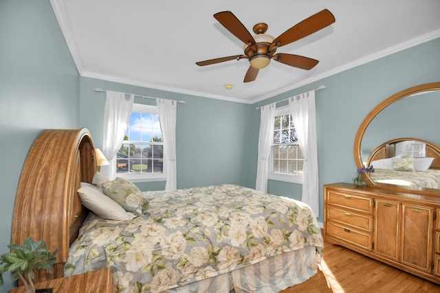 bedroom with multiple windows, crown molding, light wood-type flooring, and ceiling fan