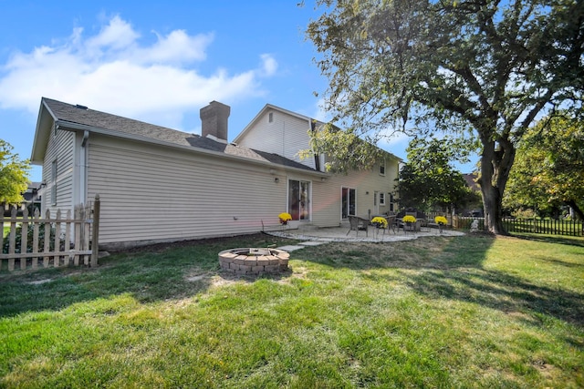 back of house with a fire pit and a lawn