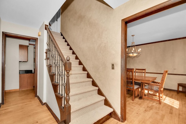 stairs featuring hardwood / wood-style flooring and a chandelier