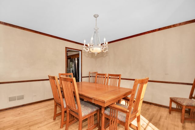 dining space featuring an inviting chandelier, ornamental molding, and light hardwood / wood-style floors