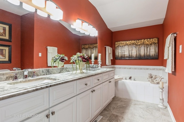 bathroom featuring a relaxing tiled tub, lofted ceiling, and vanity