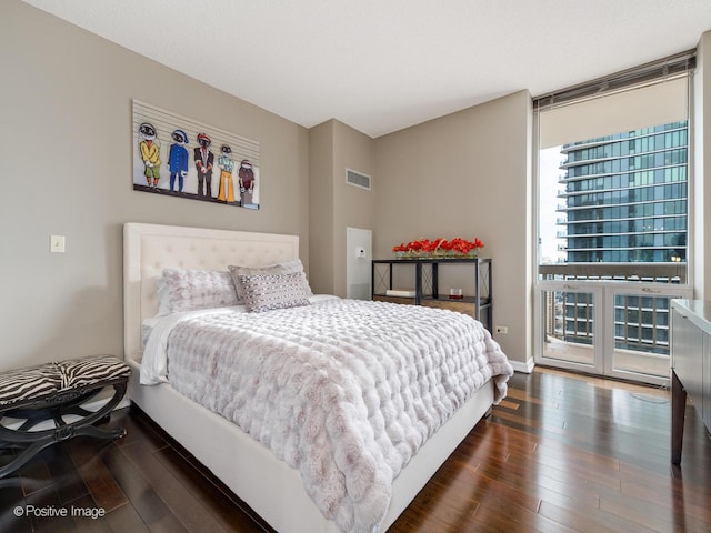 bedroom with dark wood-type flooring, expansive windows, access to outside, and visible vents