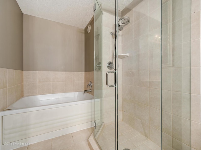 full bathroom featuring a stall shower, a garden tub, and a textured ceiling