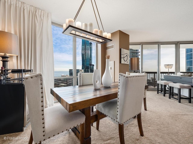 dining area featuring visible vents, light colored carpet, an inviting chandelier, a view of city, and a wall of windows