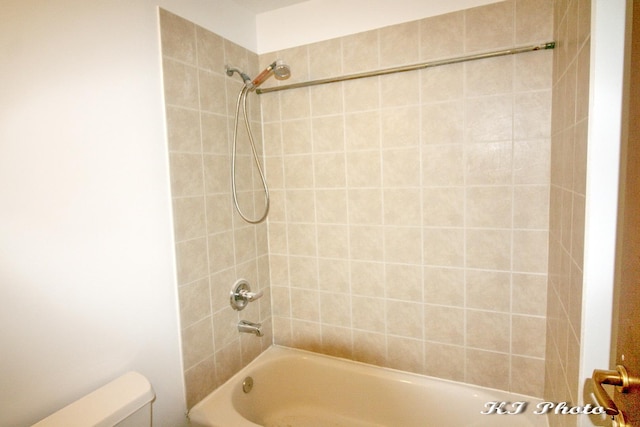 bathroom with tiled shower / bath combo and toilet