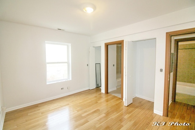 unfurnished bedroom with a closet, ensuite bath, and light hardwood / wood-style floors