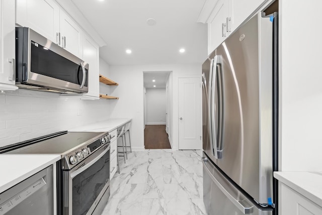 kitchen with white cabinetry, stainless steel appliances, and light stone counters