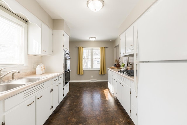 kitchen with decorative backsplash, sink, white cabinetry, and stainless steel appliances