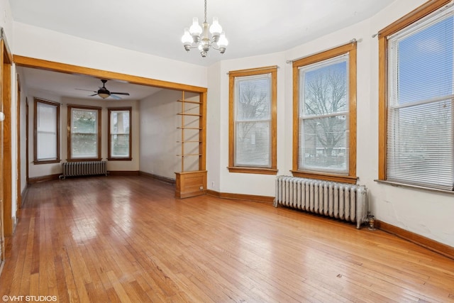 unfurnished living room featuring a notable chandelier, radiator heating unit, and wood-type flooring