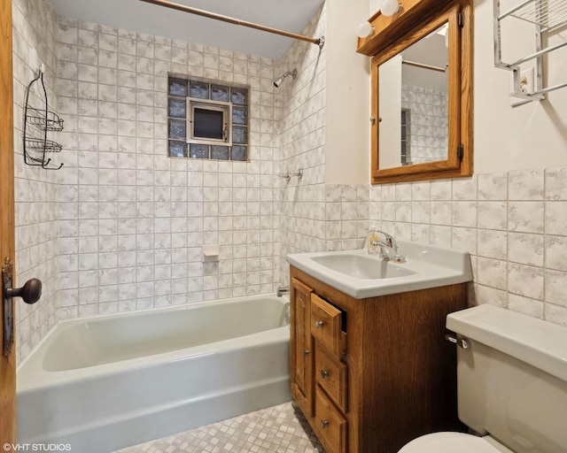 full bathroom featuring tiled shower / bath, tile walls, vanity, toilet, and tile patterned floors