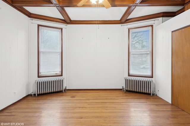 spare room with coffered ceiling, radiator, and light wood-type flooring