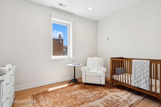 bedroom featuring a crib and wood-type flooring