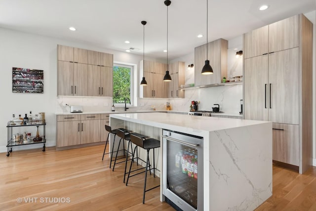 kitchen featuring wine cooler, tasteful backsplash, light hardwood / wood-style floors, a kitchen island, and light brown cabinetry