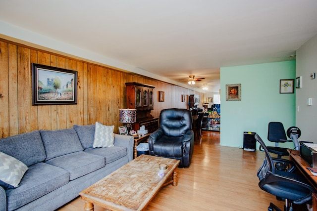 living room featuring wooden walls, ceiling fan, and light hardwood / wood-style flooring