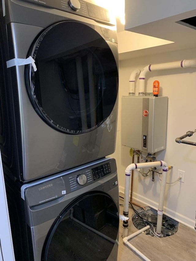 washroom with water heater and stacked washer / dryer