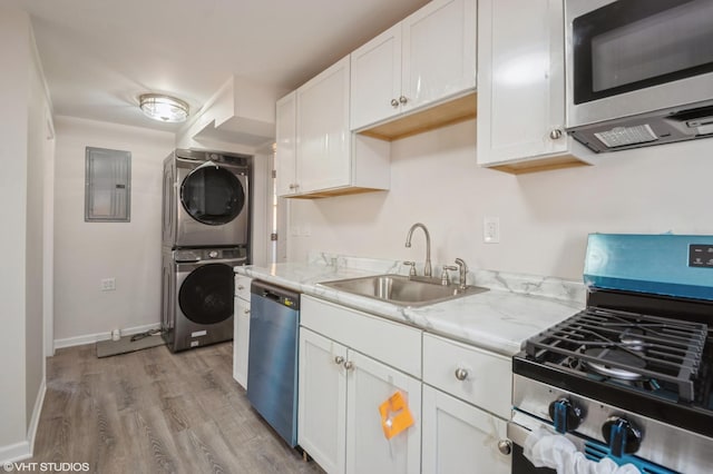 kitchen with appliances with stainless steel finishes, stacked washer / dryer, white cabinetry, sink, and electric panel