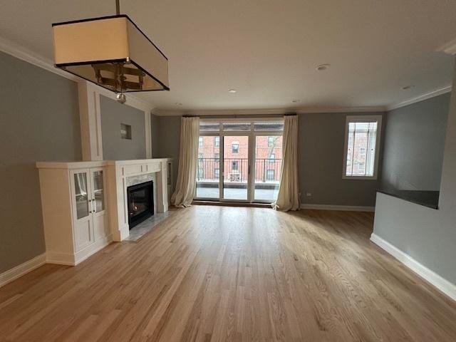 unfurnished living room with crown molding, a premium fireplace, and light hardwood / wood-style flooring