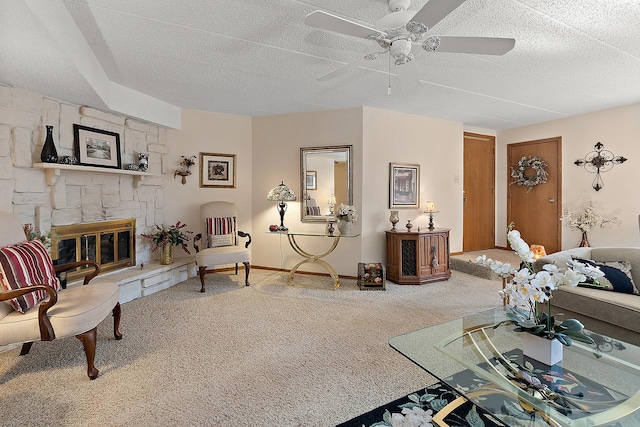 living room featuring ceiling fan, a fireplace, carpet, and a textured ceiling