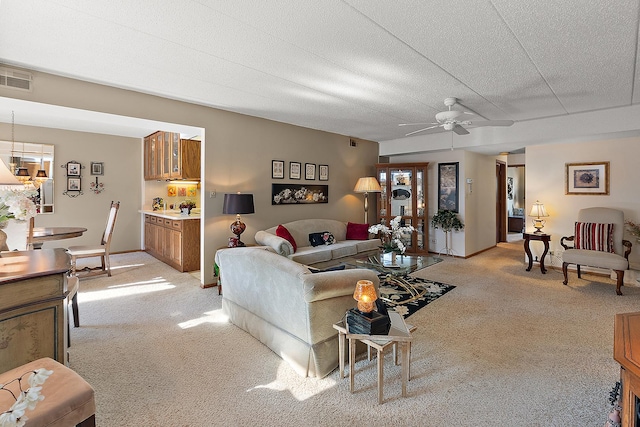 living room with ceiling fan, light colored carpet, and a textured ceiling