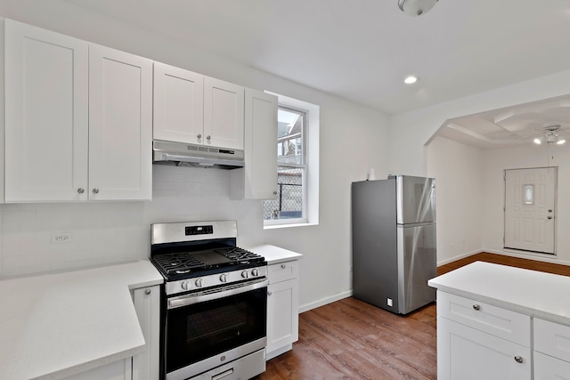 kitchen with appliances with stainless steel finishes, white cabinetry, decorative backsplash, ceiling fan, and light hardwood / wood-style floors