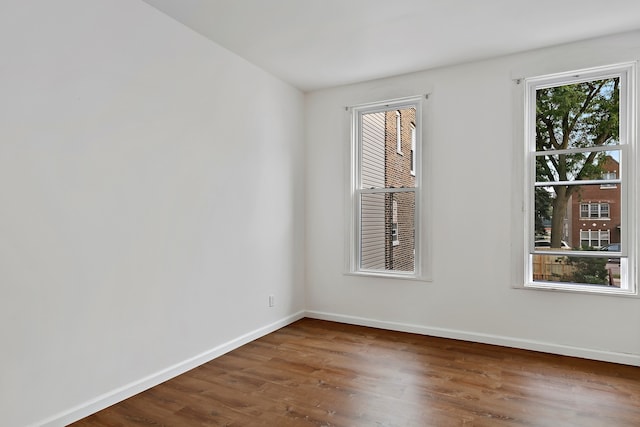 unfurnished room featuring a wealth of natural light and dark hardwood / wood-style floors