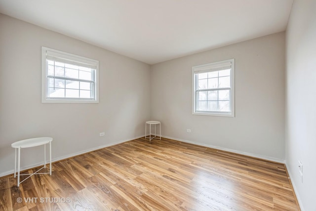 spare room featuring light wood-style flooring, baseboards, and a wealth of natural light