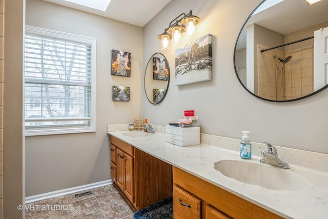 bathroom featuring a skylight, visible vents, a sink, and double vanity