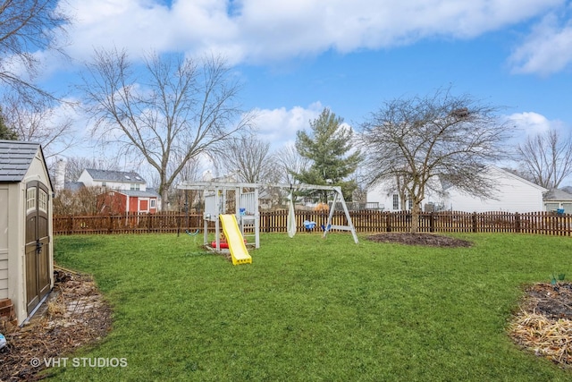 view of yard featuring a playground, an outdoor structure, a fenced backyard, and a shed