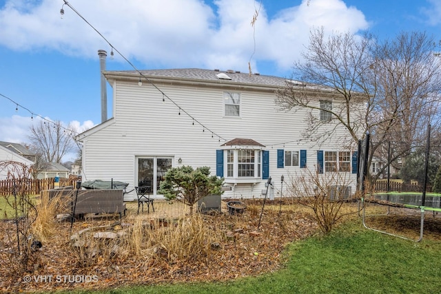 back of house featuring a patio, a trampoline, and fence