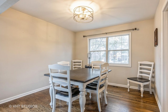 dining room with a chandelier, dark wood finished floors, and baseboards